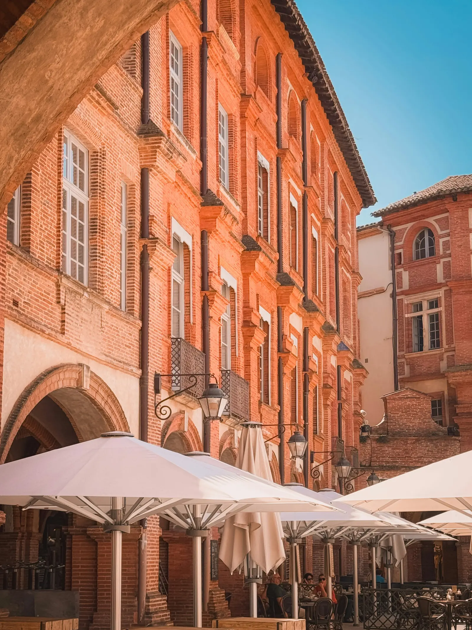 Immeubles en brique rouge et terrasses sous les arcades, à Montauban