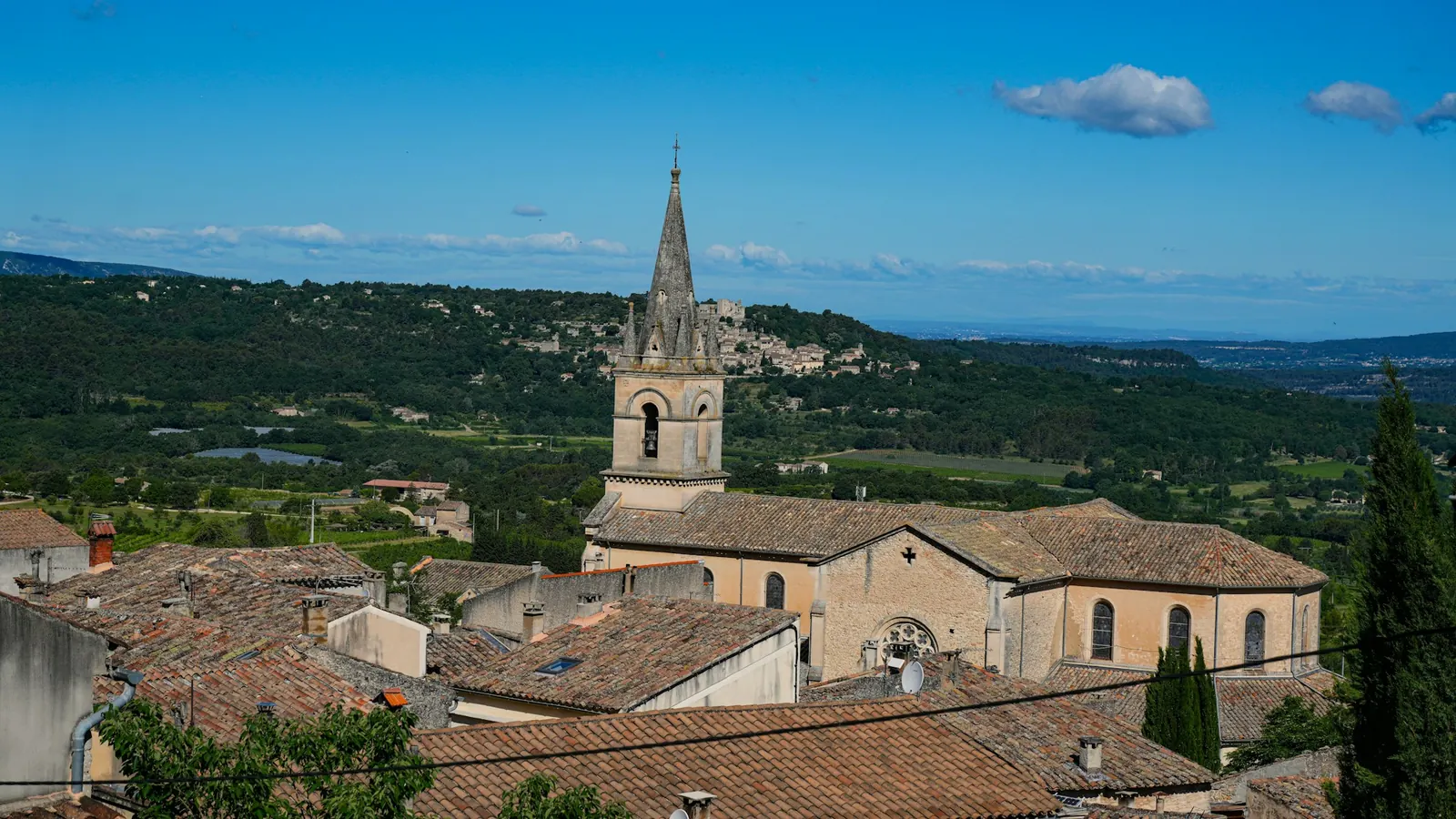 Église et toits d'un village entouré de collines vertes, photo d'illustration