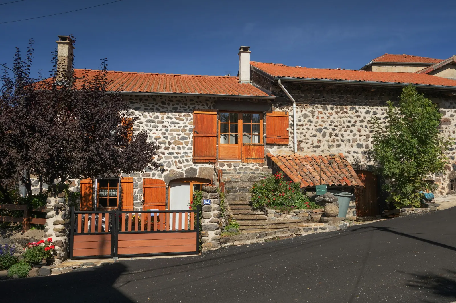 Maison en pierre aux volets orange et au toit de tuiles