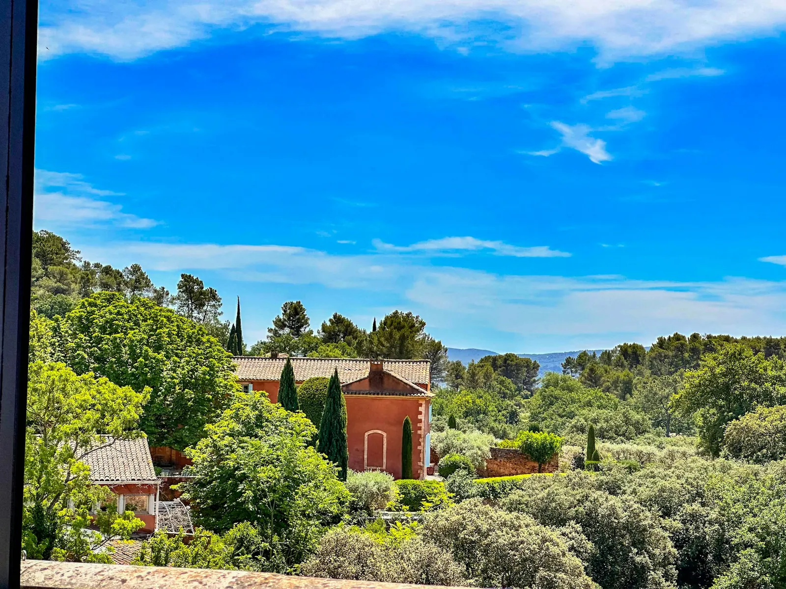 Maison rouge entourée d'arbres sous un ciel bleu