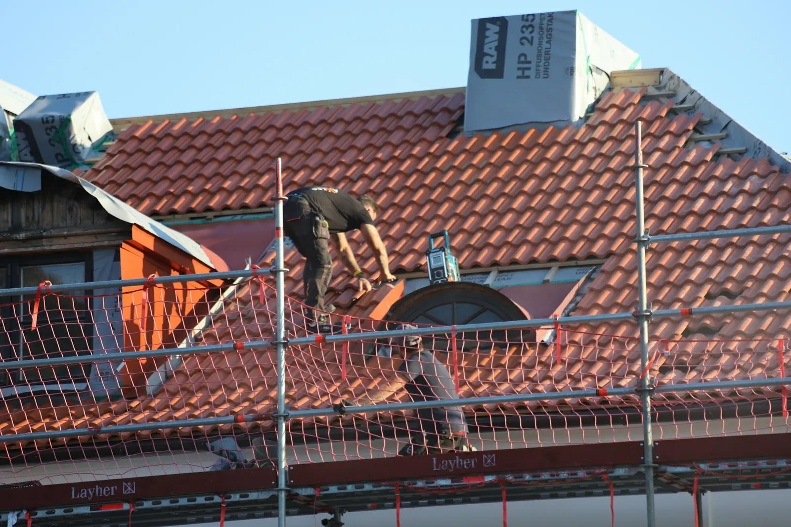 Couvreur au travail sur une toiture en tuiles, photo d'illustration